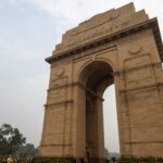 India Gate’s illuminated archway at dusk with sprawling lawns in Delhi